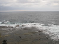 灯台崖下、日本海の荒波が岩礁に砕け散る。