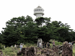 門脇灯台は、昭和35年3月に建設されましたが、平成７年５月に展望台付きの灯台に改築されました。 新灯台は、地上24.9ｍの高さですが、地上17ｍのところに収容人員30名の第一展望台（室内）が、地上４ｍの所に収容人員60名の第２展望台が設置され、晴れた日には、遠く伊豆七島や天城連山を望むことができます。
