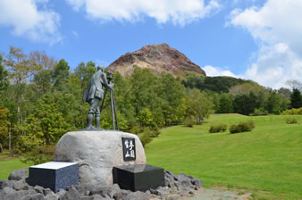 三松正夫が愛した昭和新山に観測器具を構えるようにして像が建立。