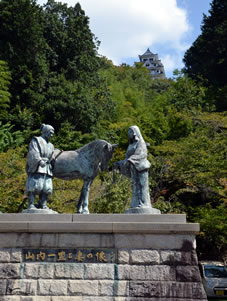 城山遊歩道の途中にある公園に建つ、山内一豊・千代の銅像。後方は天守。