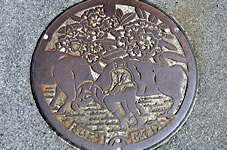 隠岐の島町のマンホール（牛突きと町の花オキシャクナゲのデザイン）
